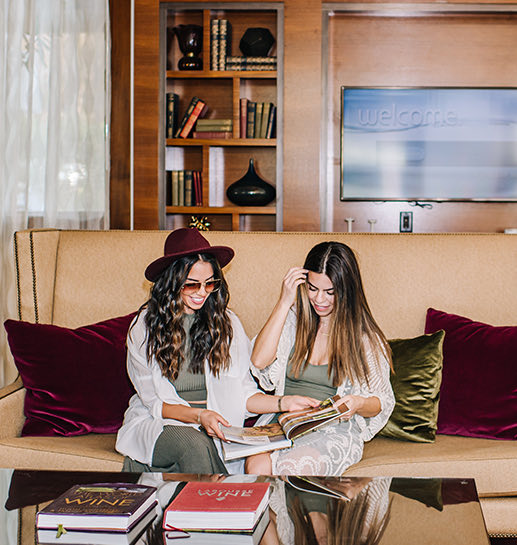 Two young ladies sitting and looking at the wine books