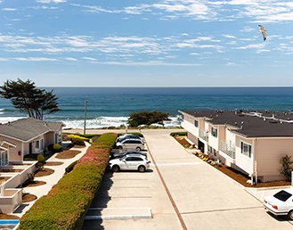 Aerial view of a hotel parking lot with the ocean on the back on a sunny day