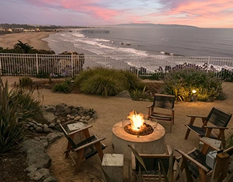 Fire pit with chairs around it at sunset with the ocean on the back