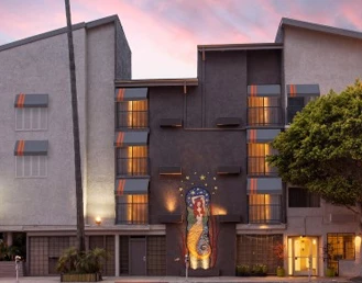 Exterior of a hotel with the lights on at sunset