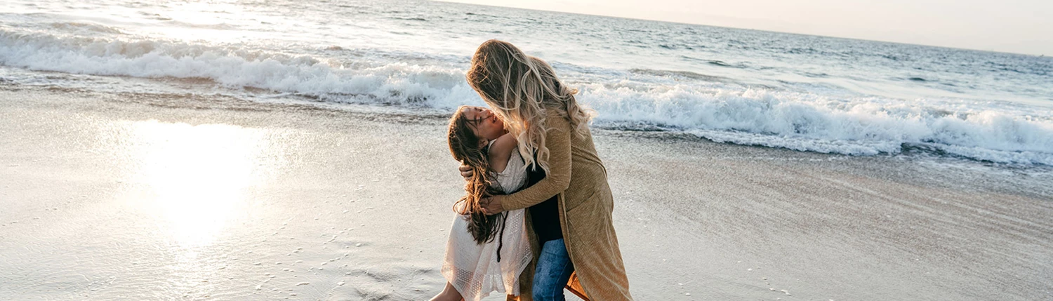a mom and her child playing on the beach