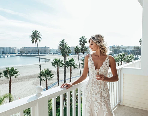 a woman in a wedding dress standing on a balcony overlooking the ocean