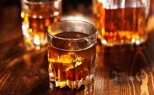 a glass of brown liquid with ice