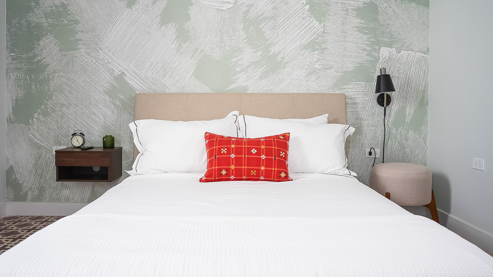 a bed with a red pillow and a lamp