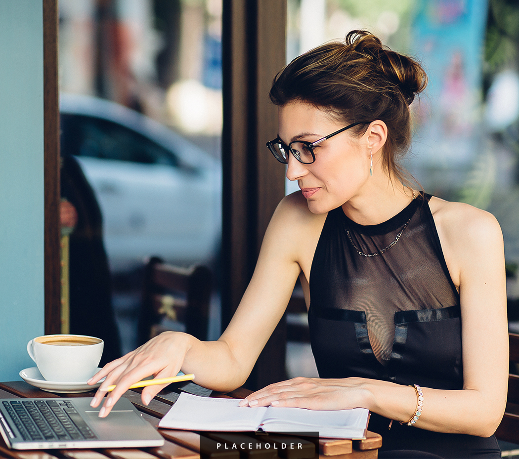 a woman sitting at a table with a laptop and a cup of coffee