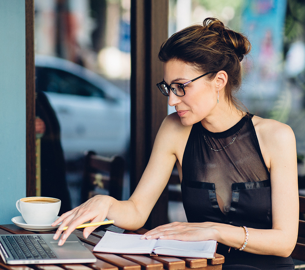 a woman sitting at a table with a laptop and a cup of coffee