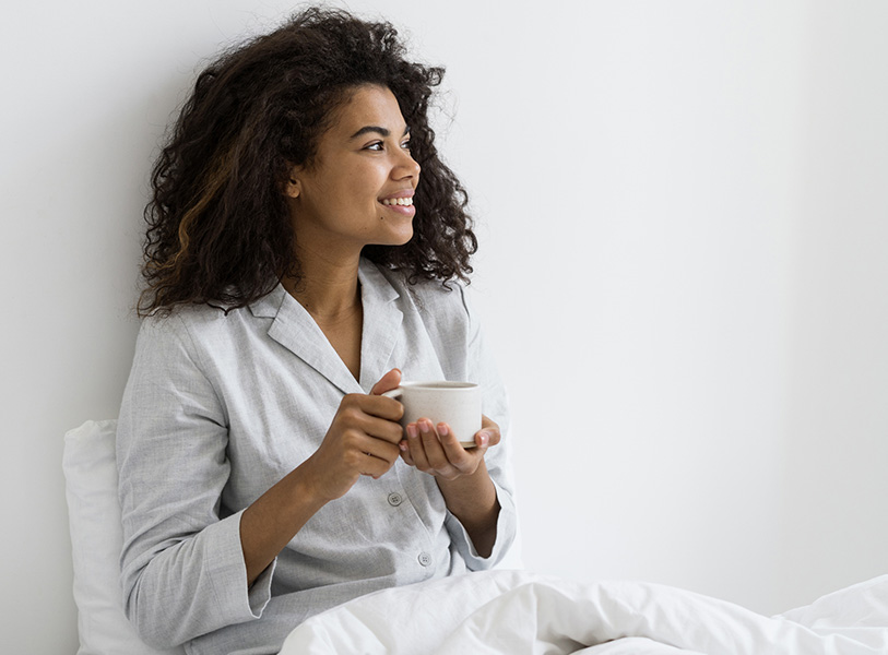 a woman in pajamas holding a cup