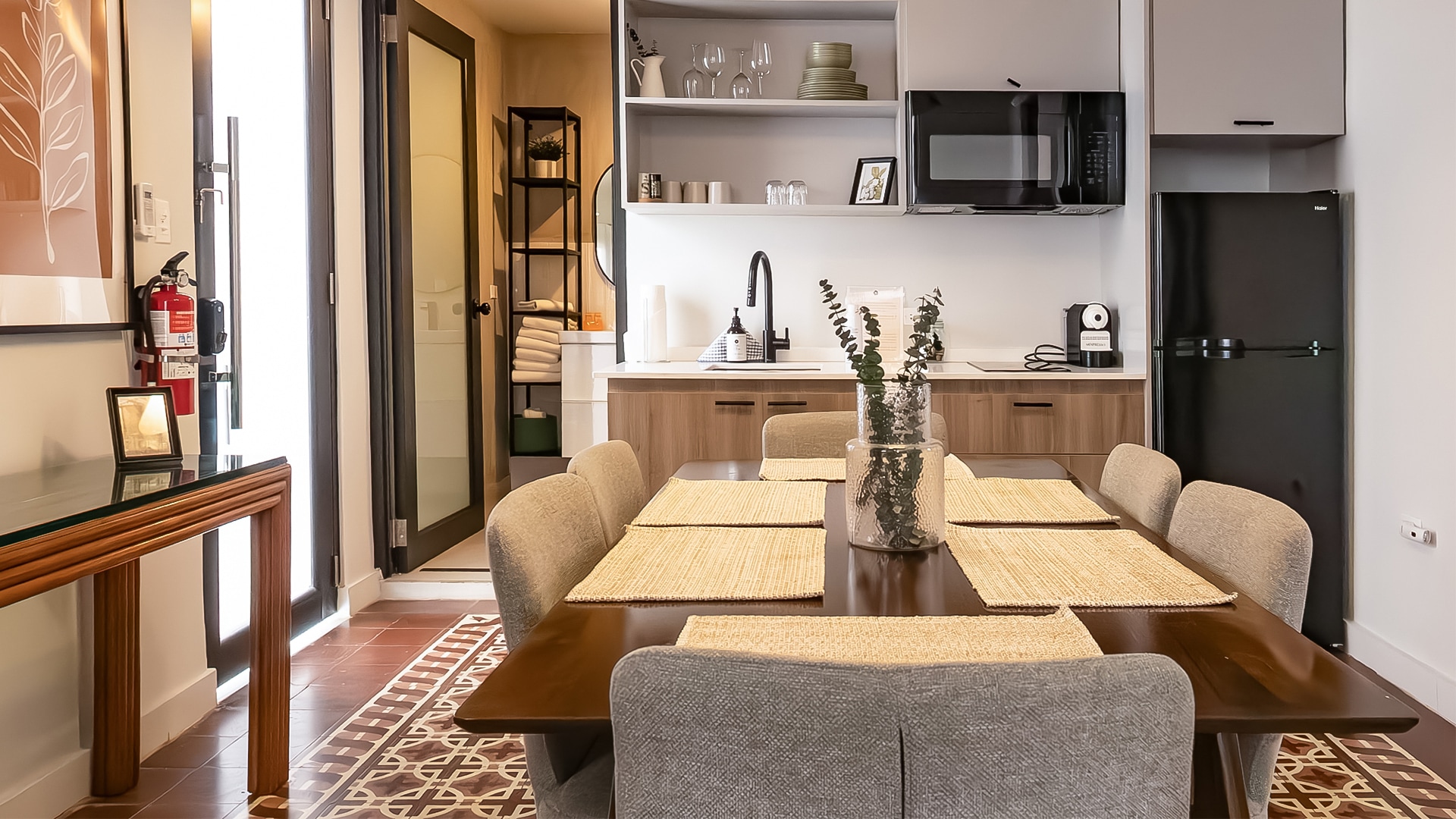 a dining table with chairs and a microwave in the background