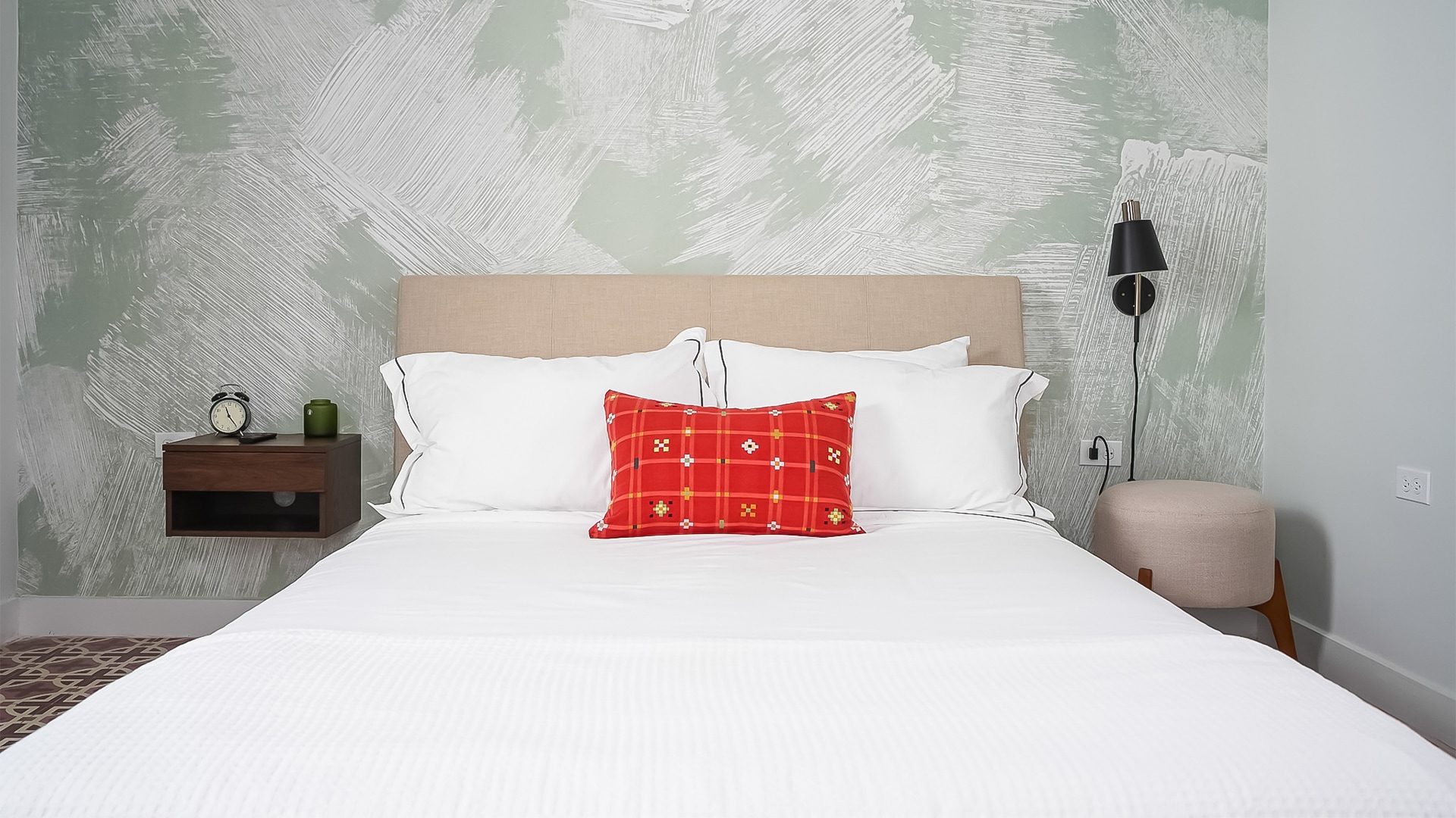 a bed with a red pillow and a lamp