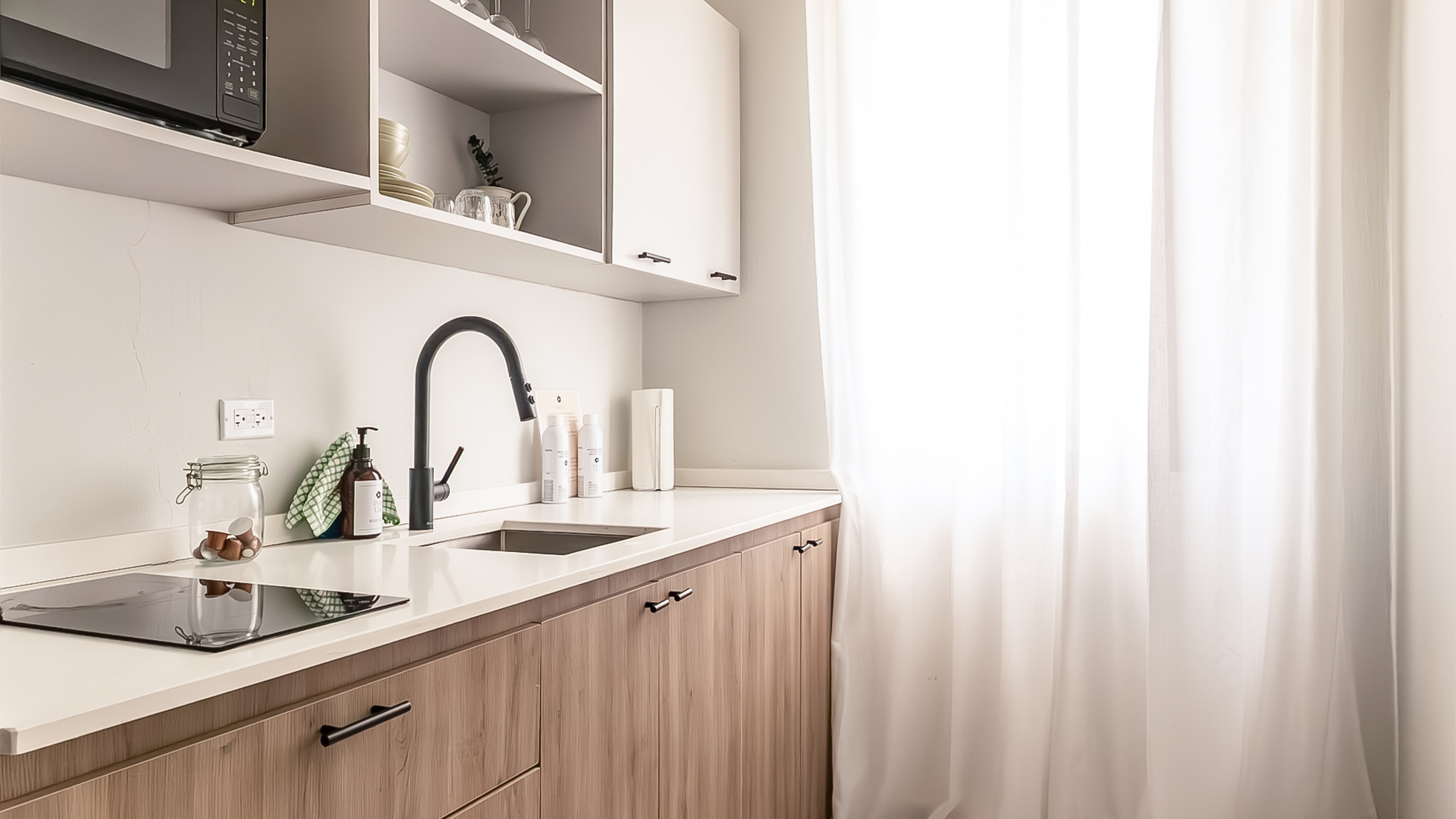 a kitchen with white cabinets and white curtains