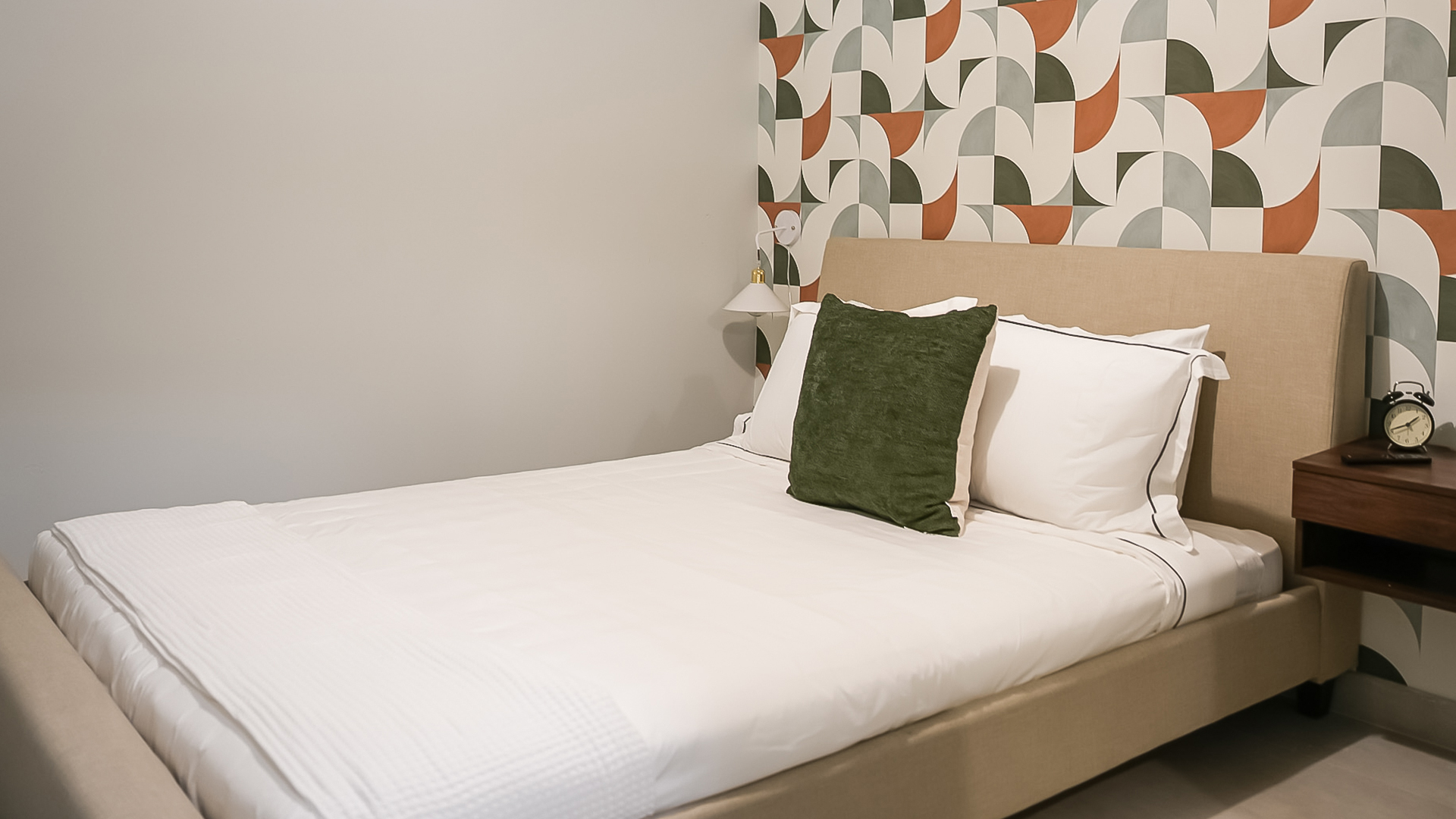 a bed with a green pillow and a lamp on the side