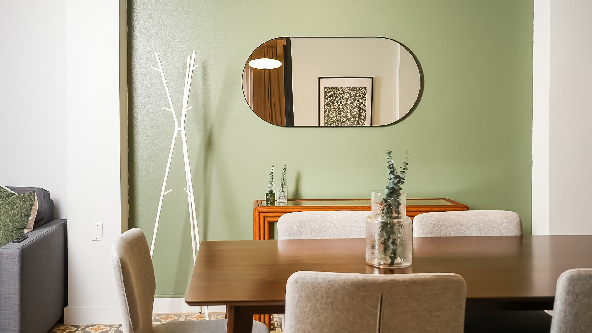 a dining table with chairs and a mirror on the wall