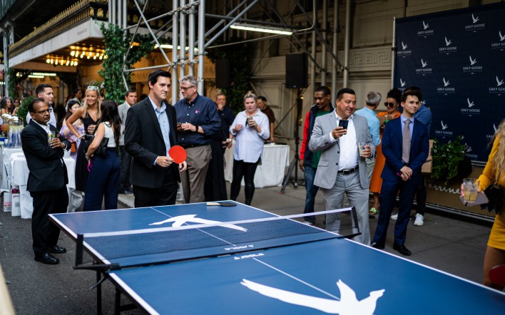 a group of people standing around ping pong table