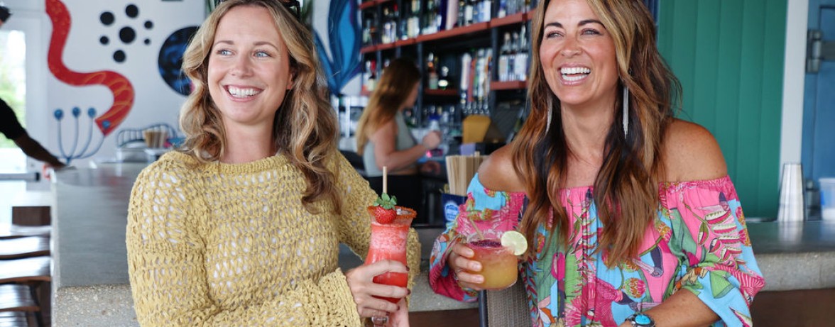 two women holding drinks in a bar