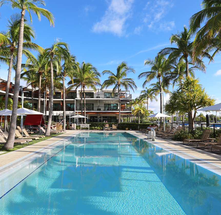side view of the long pool with palm trees and lounge chairs all around