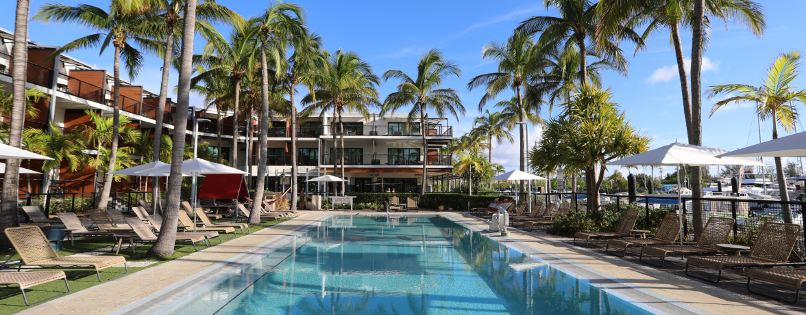 a pool with palm trees and a building