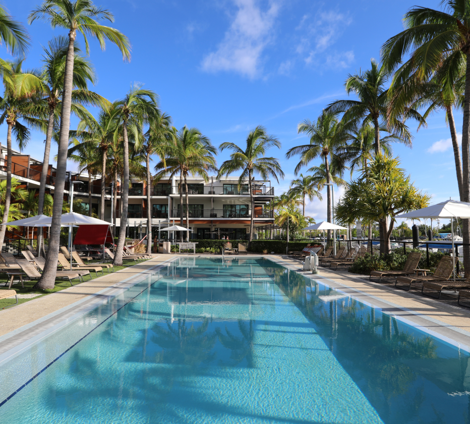 a pool with palm trees and a building
