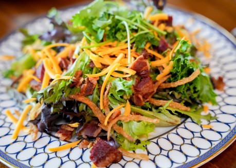 a salad with bacon and cheese on a plate