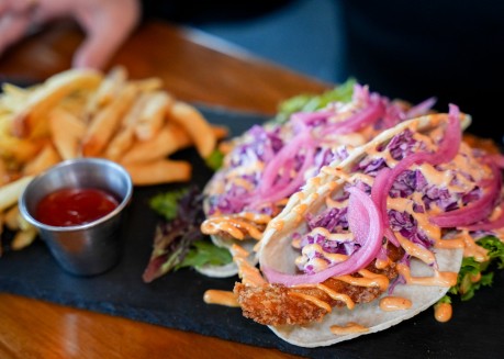 a tacos with sauce and fries on a black plate