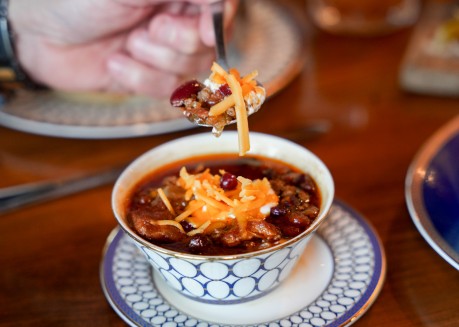 a person holding a spoon over a bowl of soup