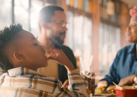 a child eating food at a table with a man and woman