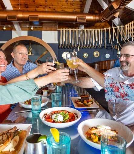 a group of people sitting at a table with food and drinks