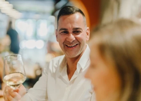 a man in a white shirt holding a wine glass