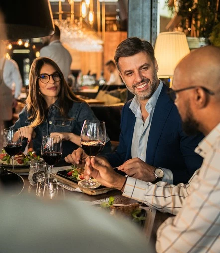 a group of people sitting at a table with food and drinks