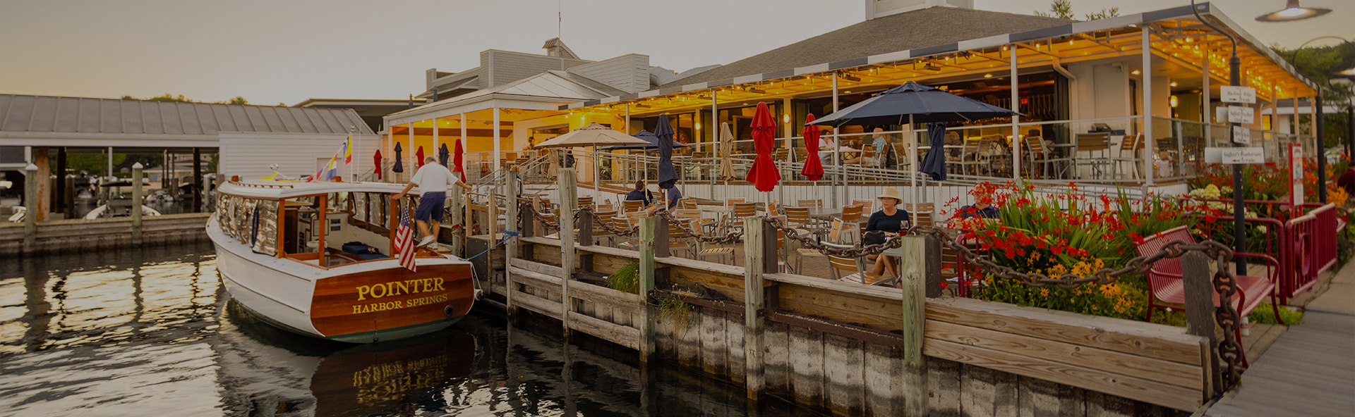 a group of people sitting at a dock with umbrellas and a boat