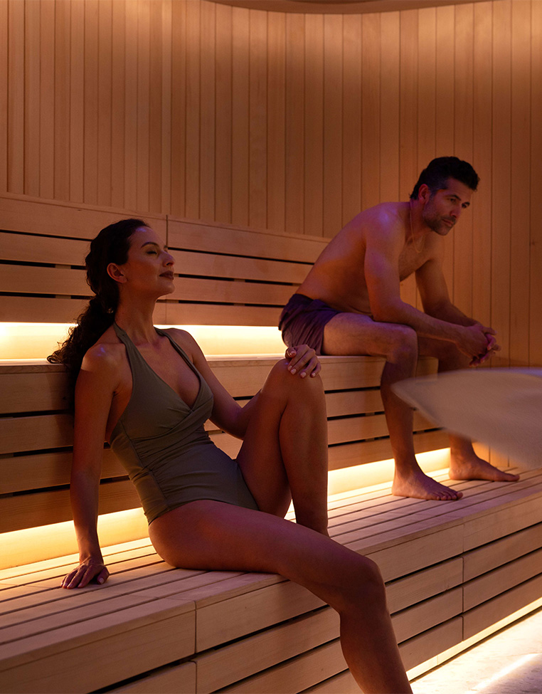 a man and woman sitting on a bench in a sauna