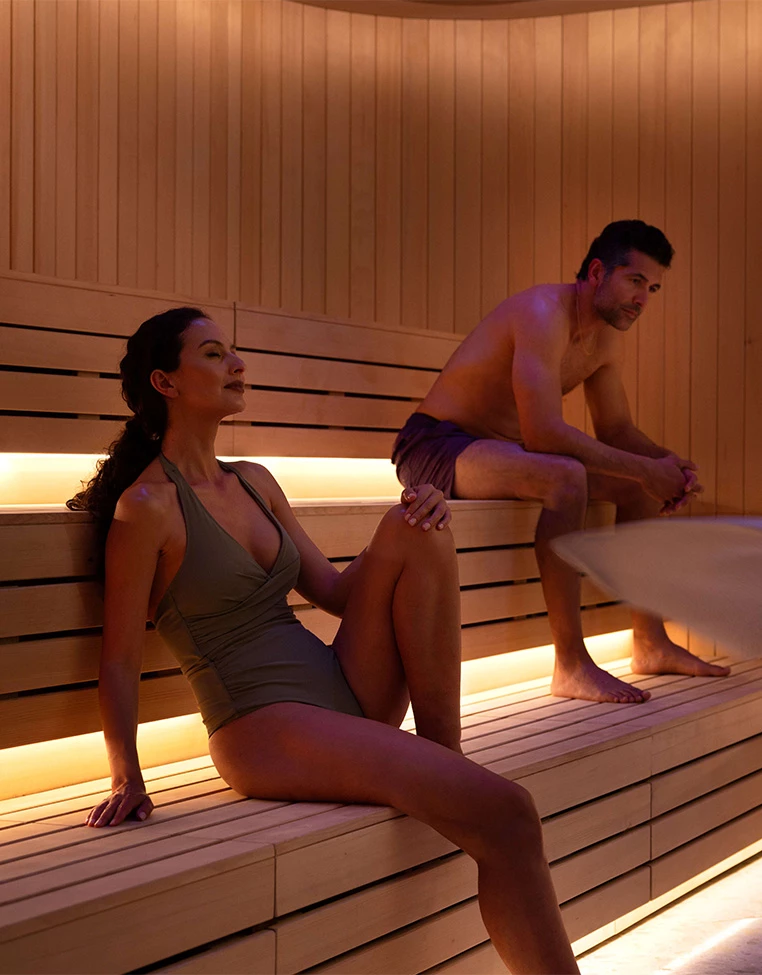 a man and woman sitting on a bench in a sauna