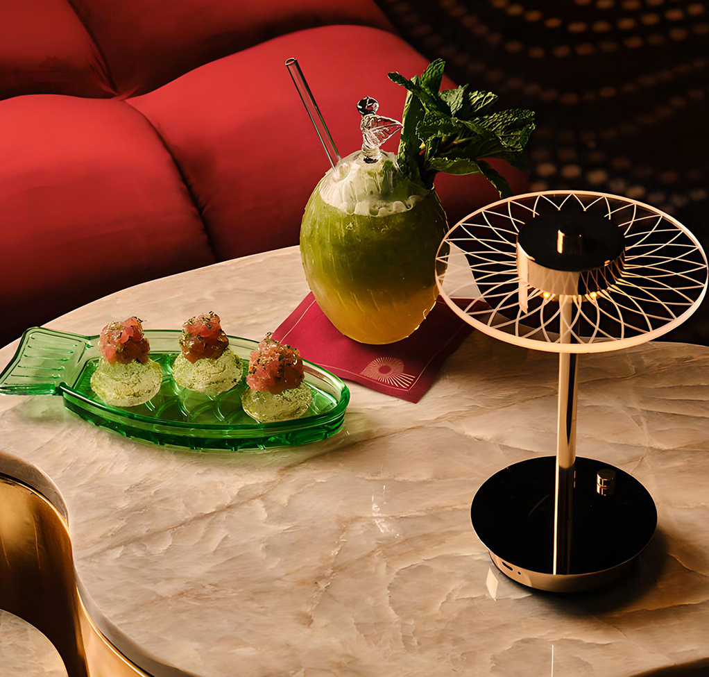 a table with a drink and a lamp