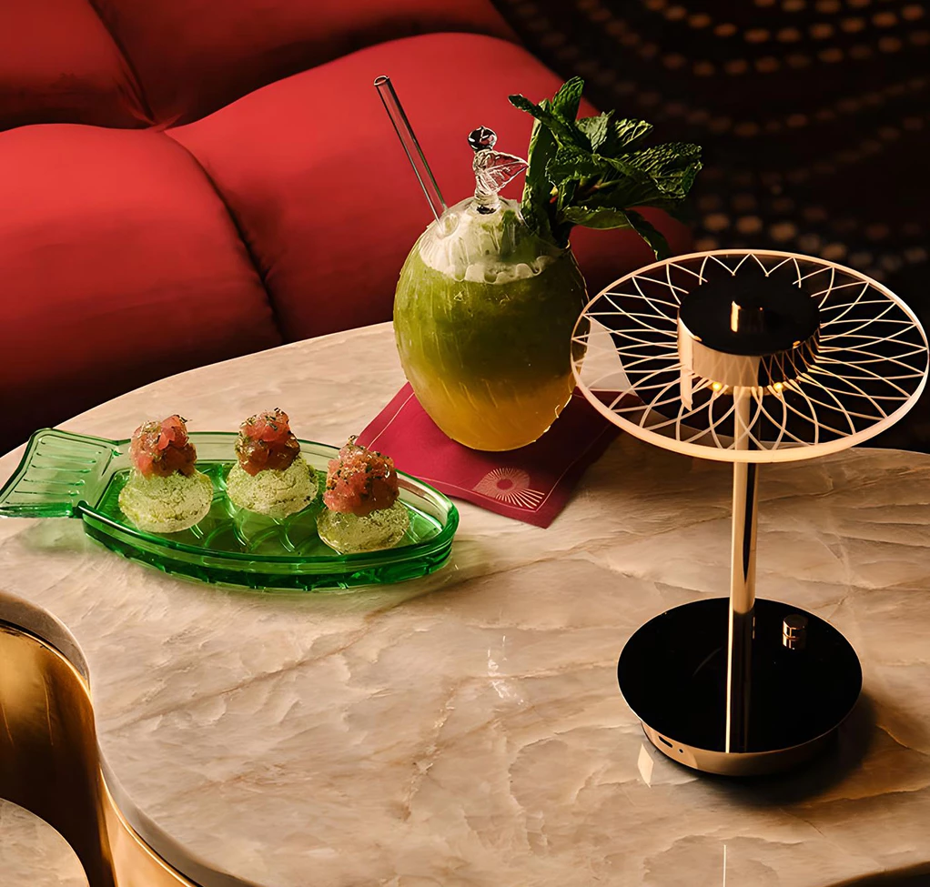 a table with a drink and a lamp