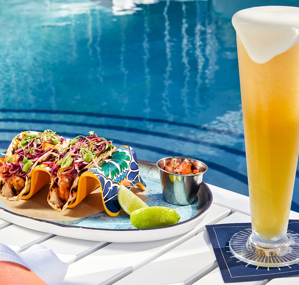 a taco on a plate next to a glass of beer