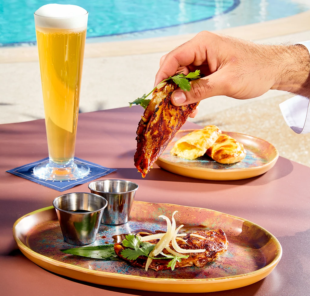 a hand holding a piece of meat over a plate of food