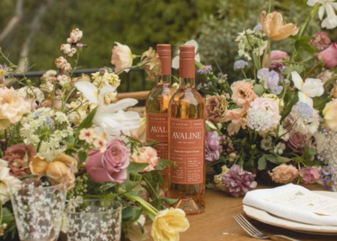 a couple of bottles of wine on a table with flowers