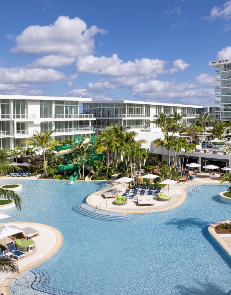 a pool with chairs and a slide in front of a building