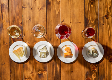 a group of plates of cheese and wine on a table 