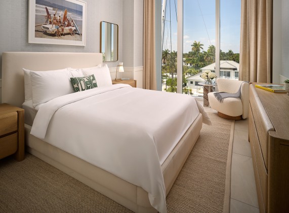 a bed with a chair and a chair in a room with a view of the ocean