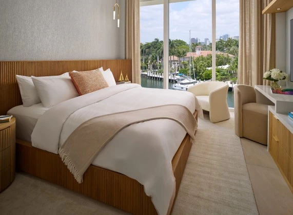 a bedroom with a bed and chairs and a view of a city