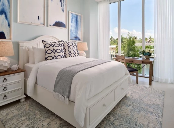 a bed with a white bed frame and a table with chairs and a desk