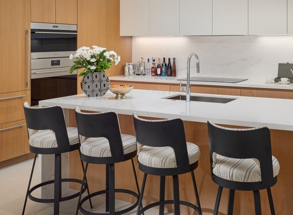 a kitchen with a white countertop and black chairs