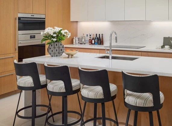 a kitchen with a white countertop and black chairs