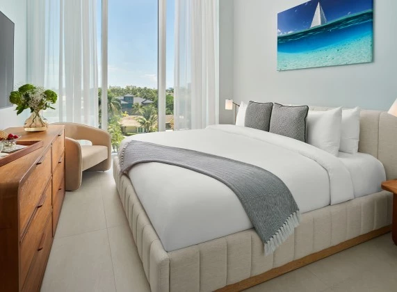 a bed with a chair and a table in a room with windows