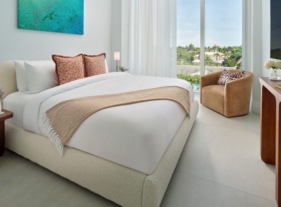 a bed with a chair and a painting on the wall