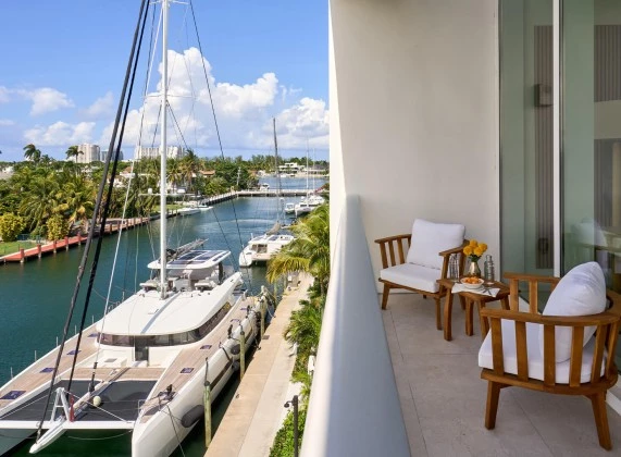 a balcony with chairs and a table and a boat in the water