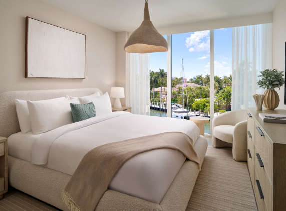 a bedroom with a bed and chairs and a large window