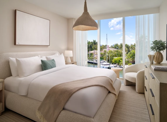 a bedroom with a bed and chairs and a large window