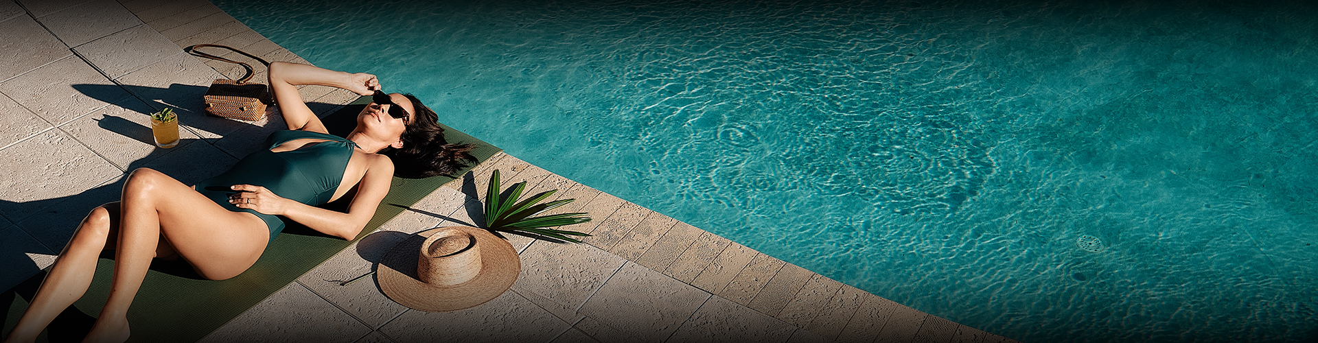 a hat and palm leaf next to a pool