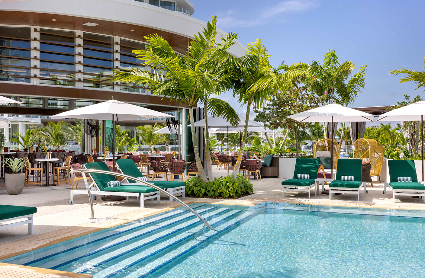 a pool with chairs and umbrellas by a building